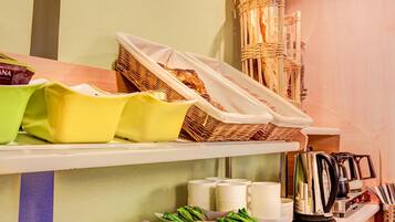 A kitchen area with shelves holding bread, utensils, and kitchenware.