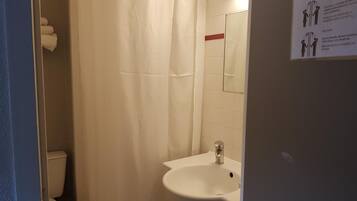 A small bathroom with a white sink, a toilet, and a shower curtain.