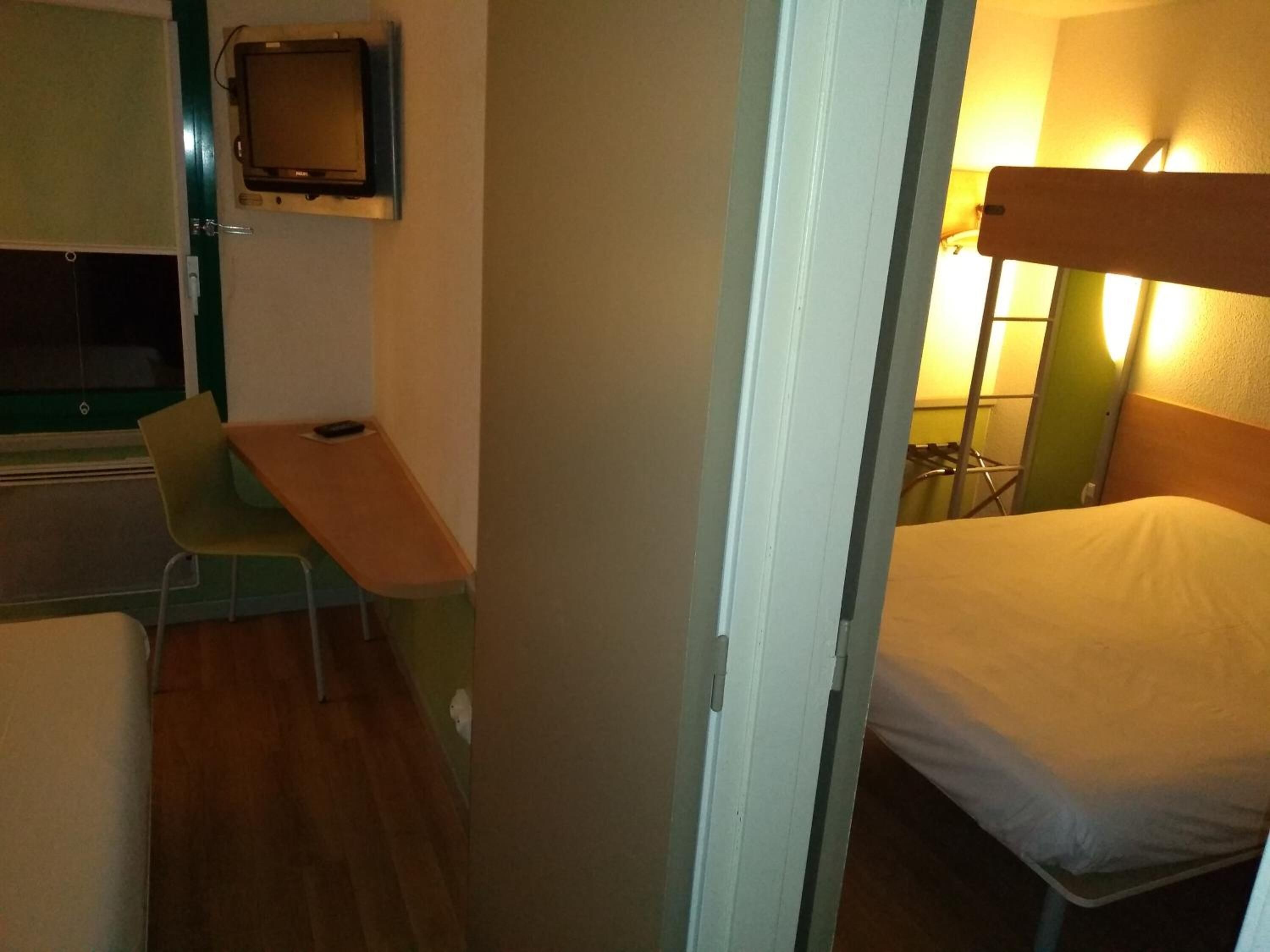 Una habitación pequeña con una cama, un escritorio y una silla.