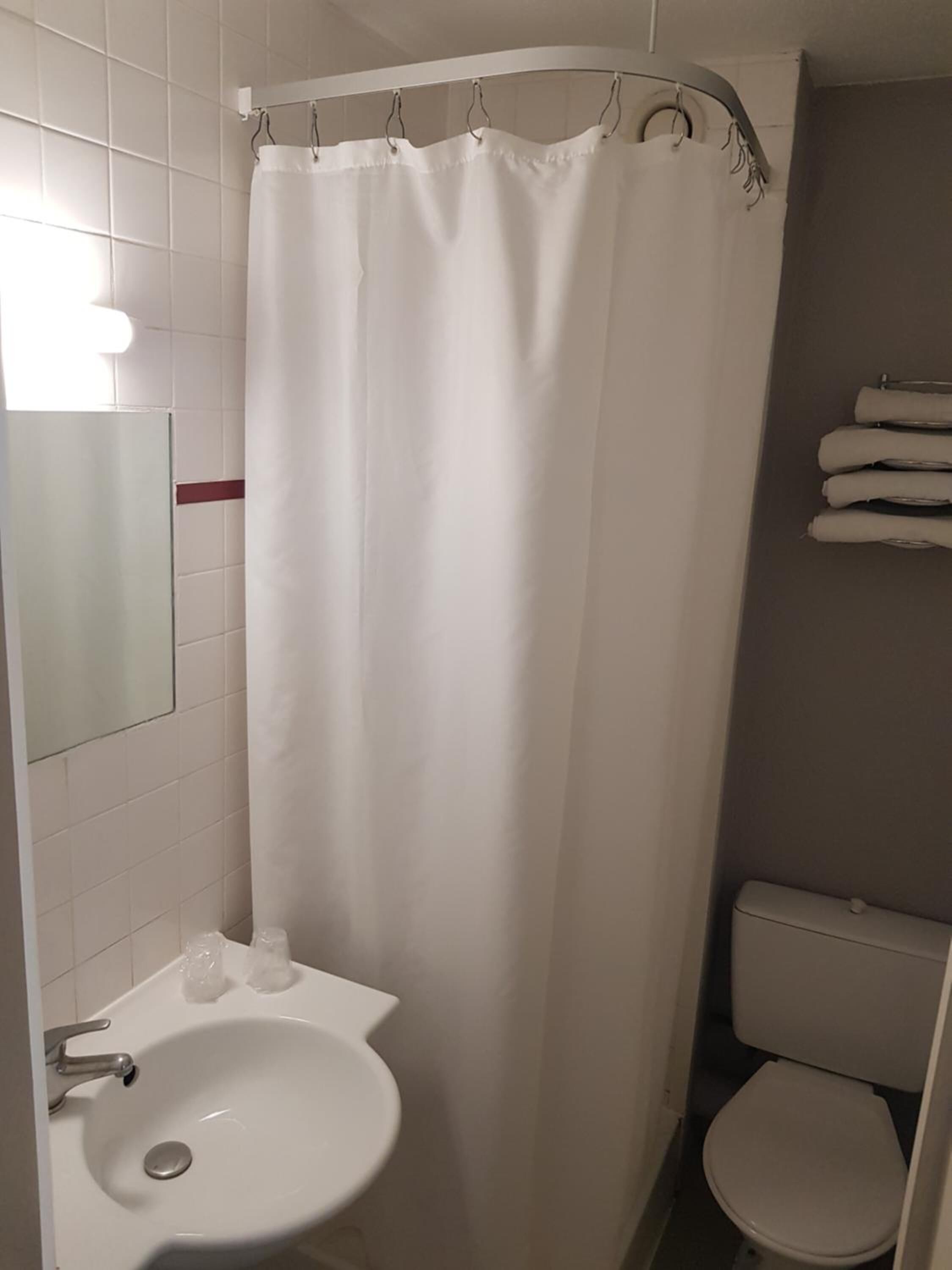 A bathroom with a white sink, a toilet, and a shower curtain.