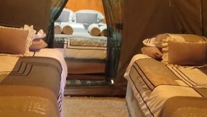 Une pièce aménagée comme une tente, avec deux lits, chacun équipé d’oreillers et d’une couverture.