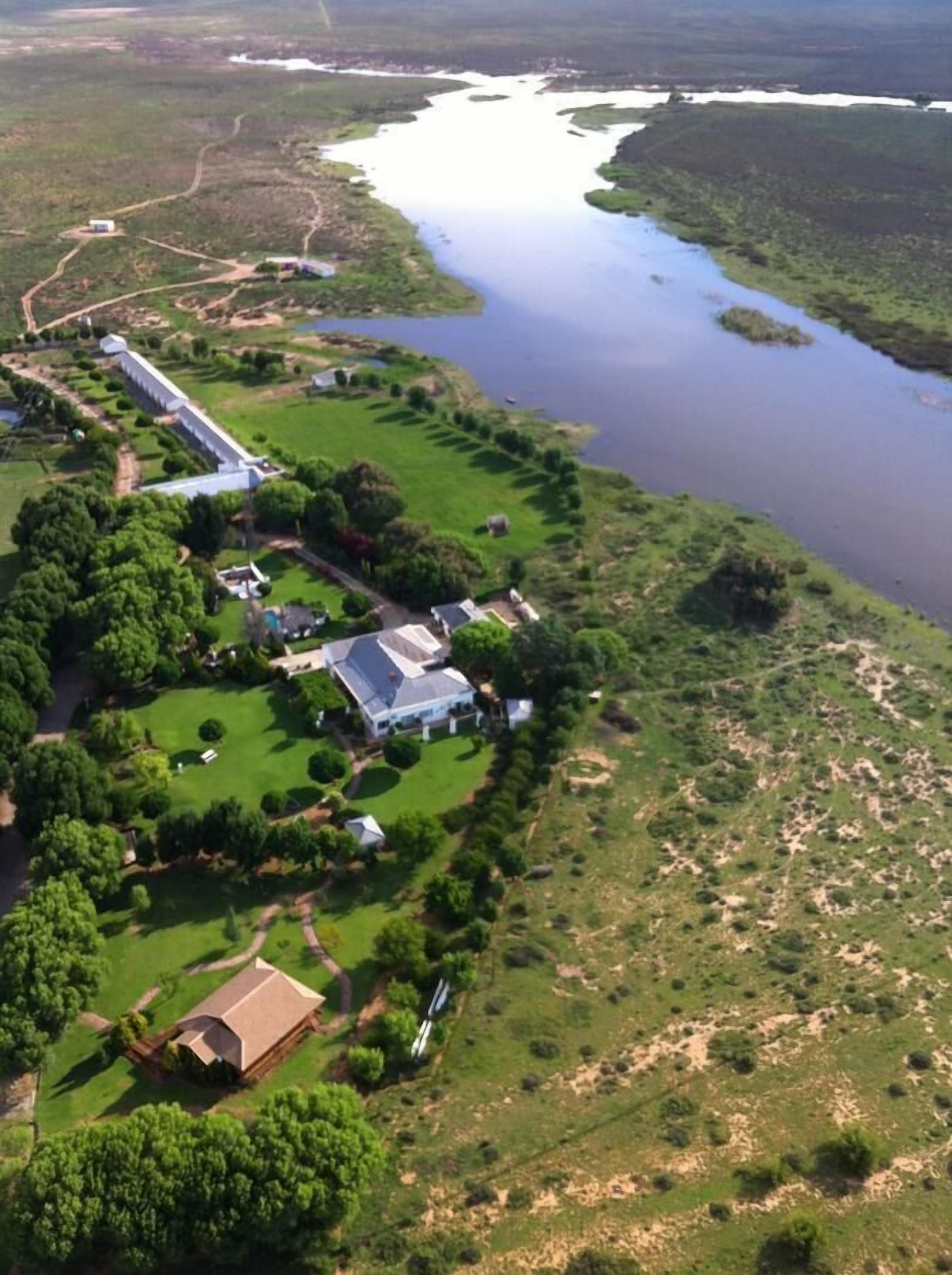 A large estate with multiple buildings, a long driveway, and a lake.