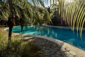 A swimming pool surrounded by palm trees and a stone pathway. - Coco Breeze Private Residence (Sardinal)