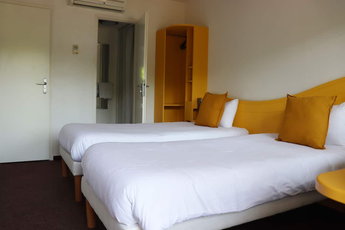 Ein Hotelzimmer mit zwei Betten, einem Kleiderschrank und einem kleinen Tisch.