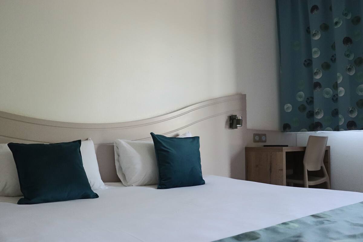 Ein Hotelzimmer mit Bett, Kissen, Schreibtisch und Stuhl.