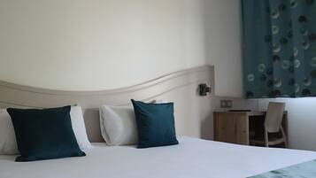 Ein Hotelzimmer mit Bett, Kissen, Schreibtisch und Stuhl.