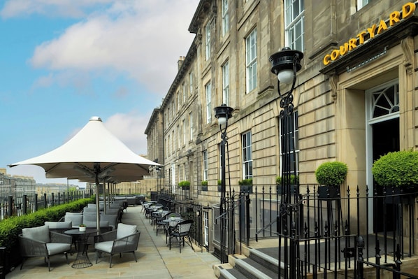 A courtyard with outdoor seating, a large umbrella, and a building labeled "COURTYARD".