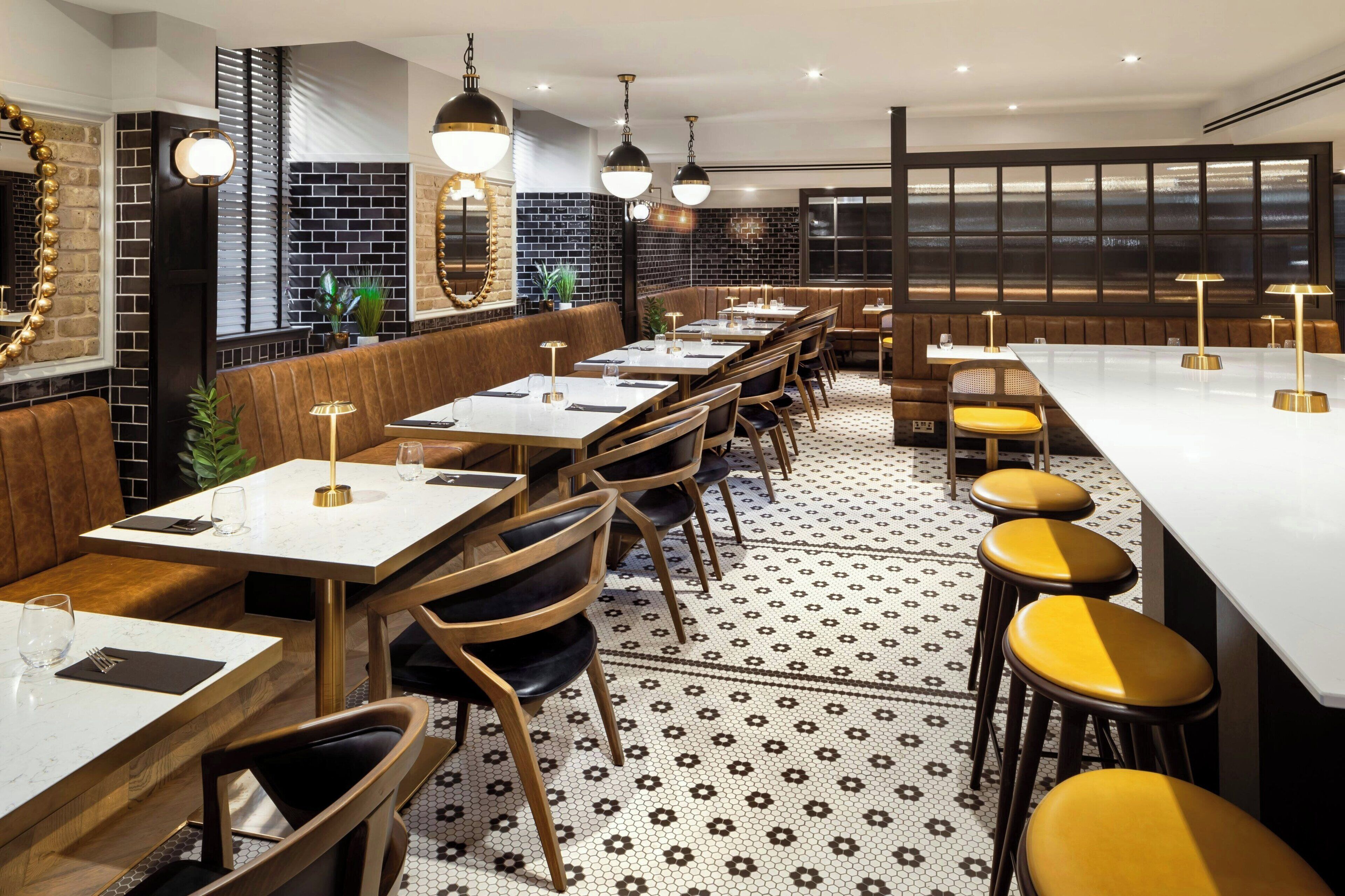 Un restaurante con mesas largas compartidas, cabinas y taburetes altos.