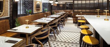A restaurant with long communal tables, booths, and high stools.