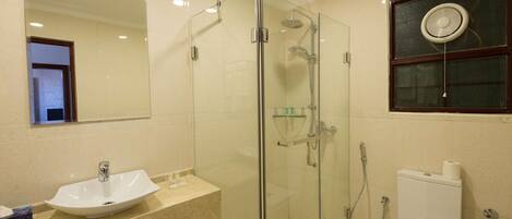 Une salle de bain avec une douche à parois de verre, un lavabo et des toilettes.