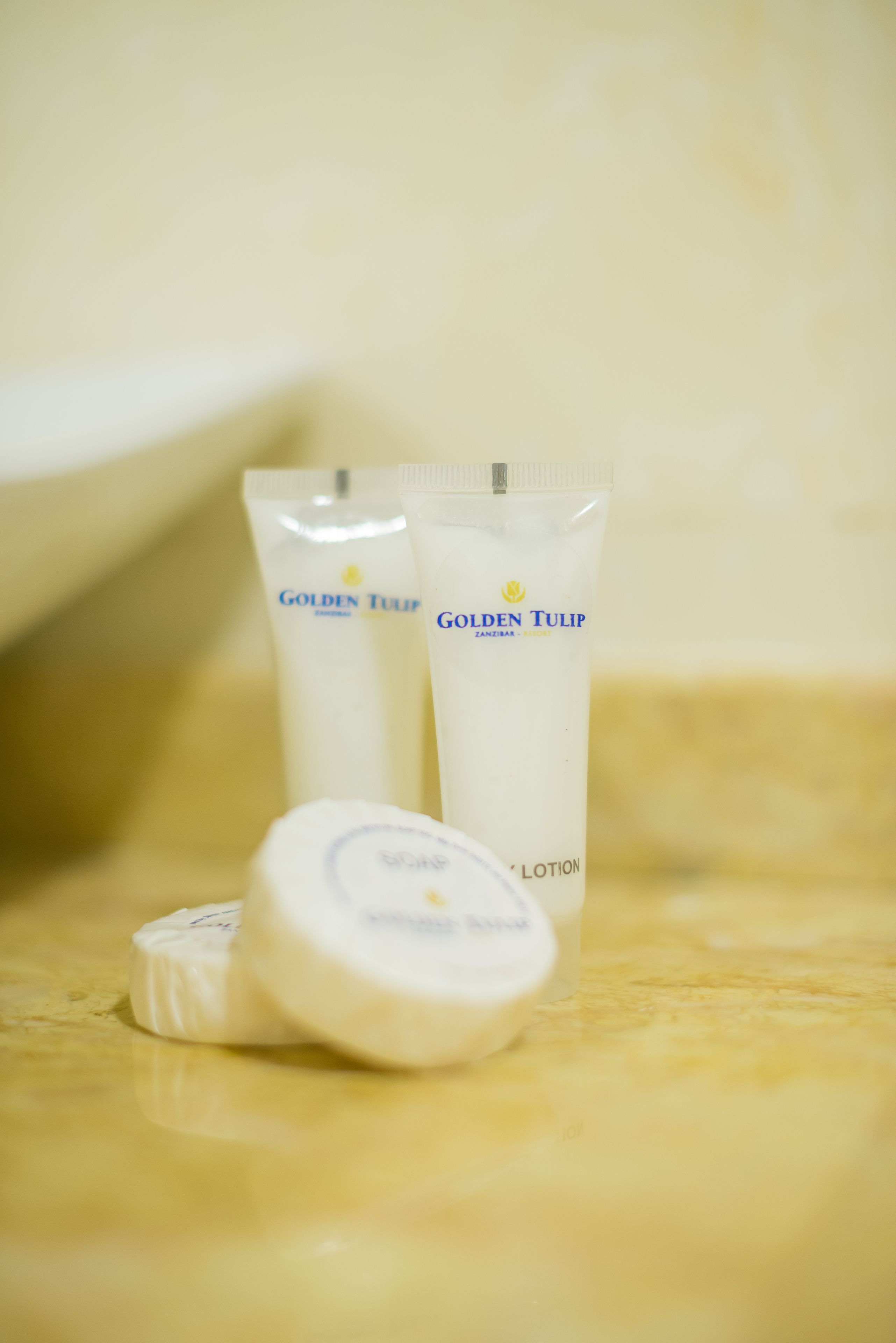 Two tubes of Golden Tulip lotion and a round container on a marble surface.