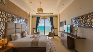 Habitación de hotel con una cama grande, un escritorio, un televisor y vista al océano.
