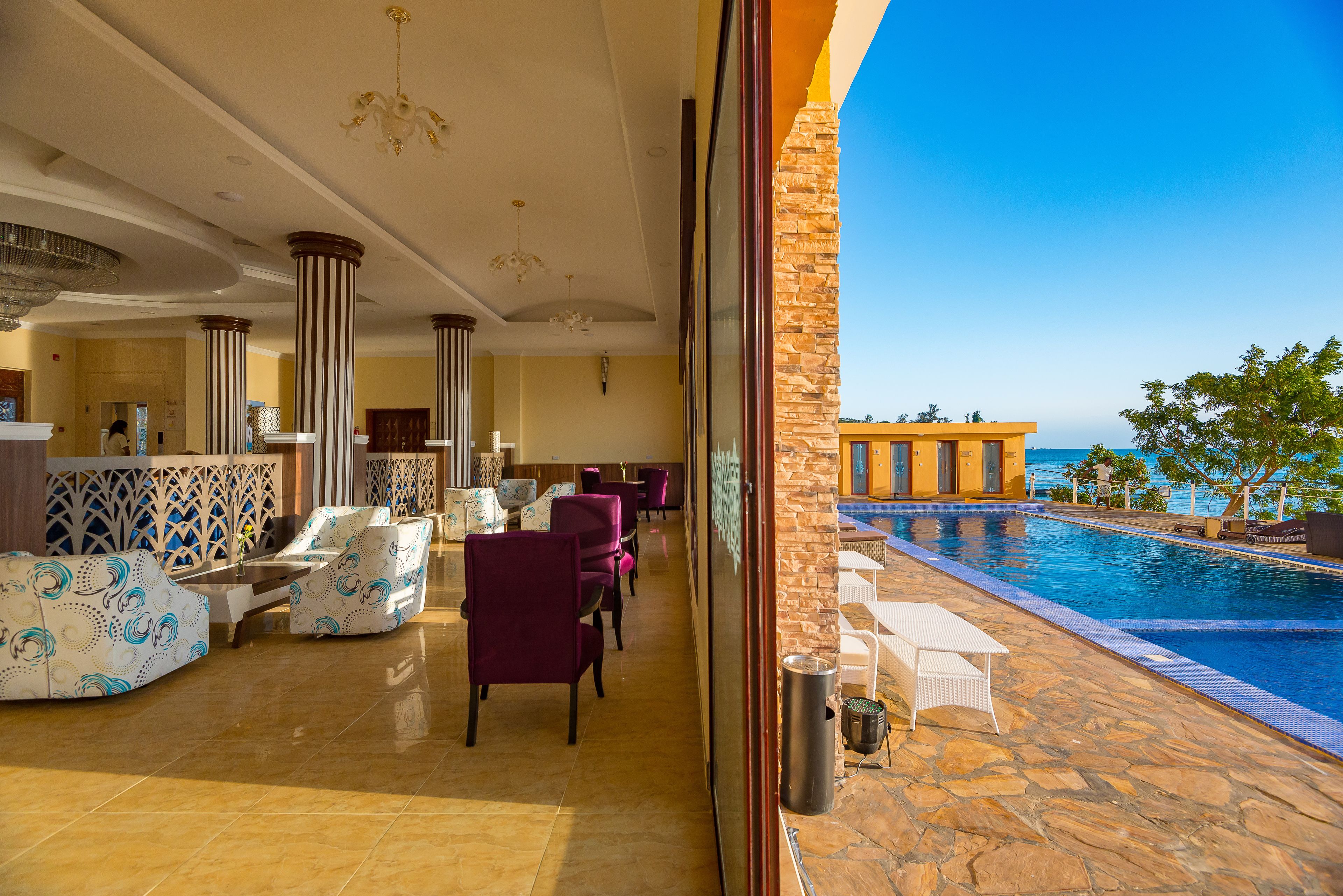 A hotel lobby with a pool, seating areas, and a view of the ocean.