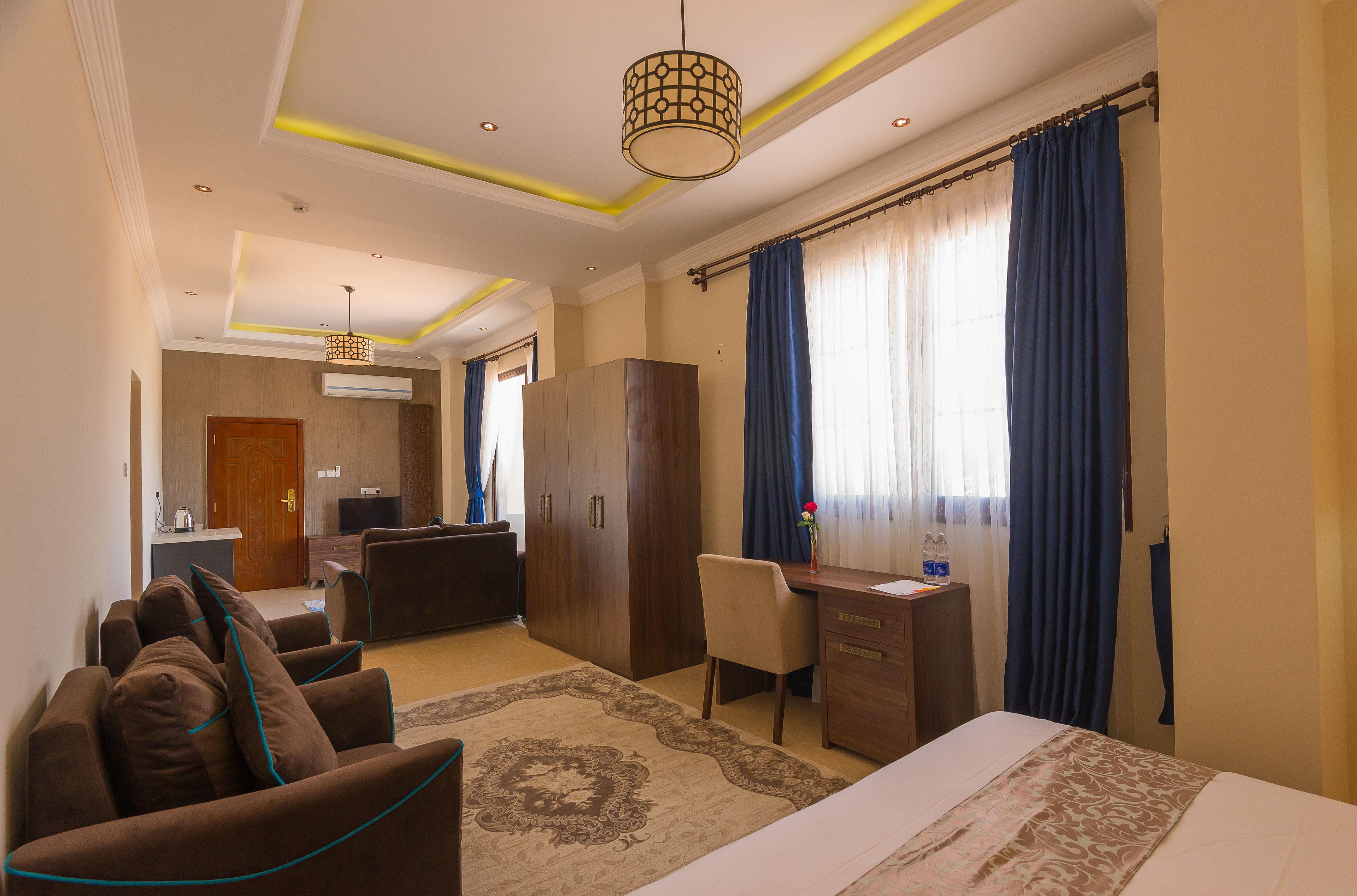 A hotel room with a bed, a desk, a chair, a sofa, and a wardrobe.
