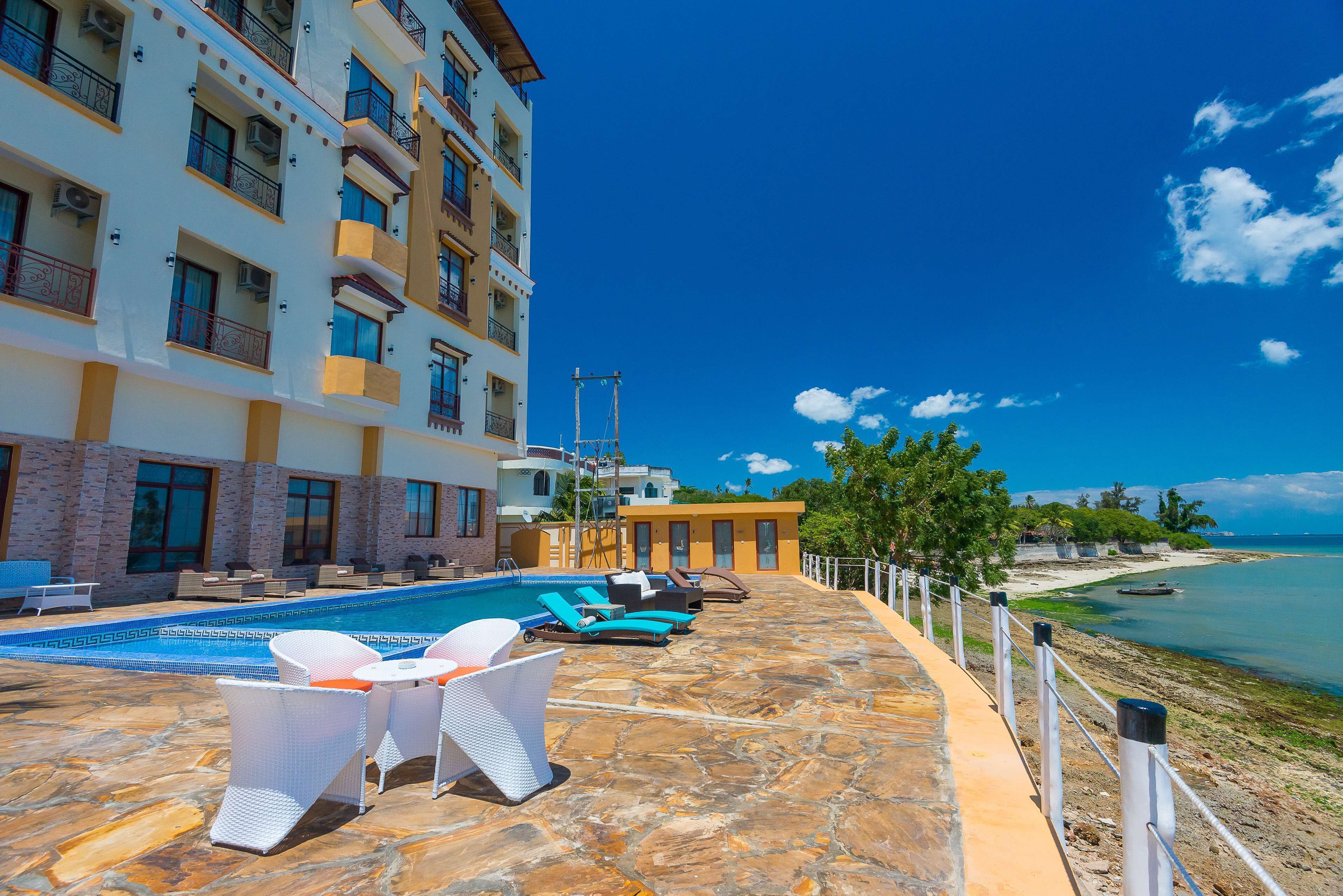 A poolside area with lounge chairs and a swimming pool, overlooking a beach and ocean.