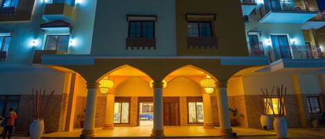 A hotel entrance with a covered walkway, columns, and a well-lit facade.
