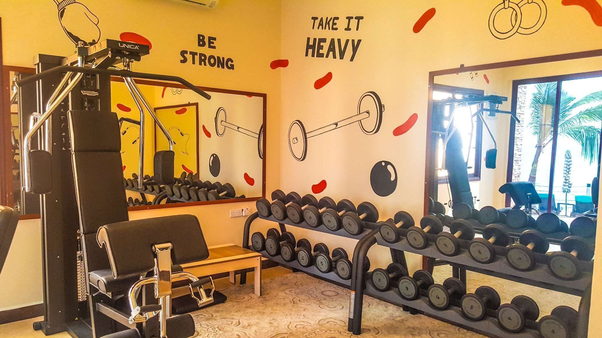 Une salle de sport équipée de matériel d’exercice, d’un banc et d’un porte-haltères.