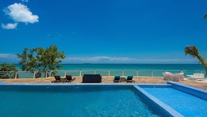 Zona de piscina con sillones de descanso y vista al océano.