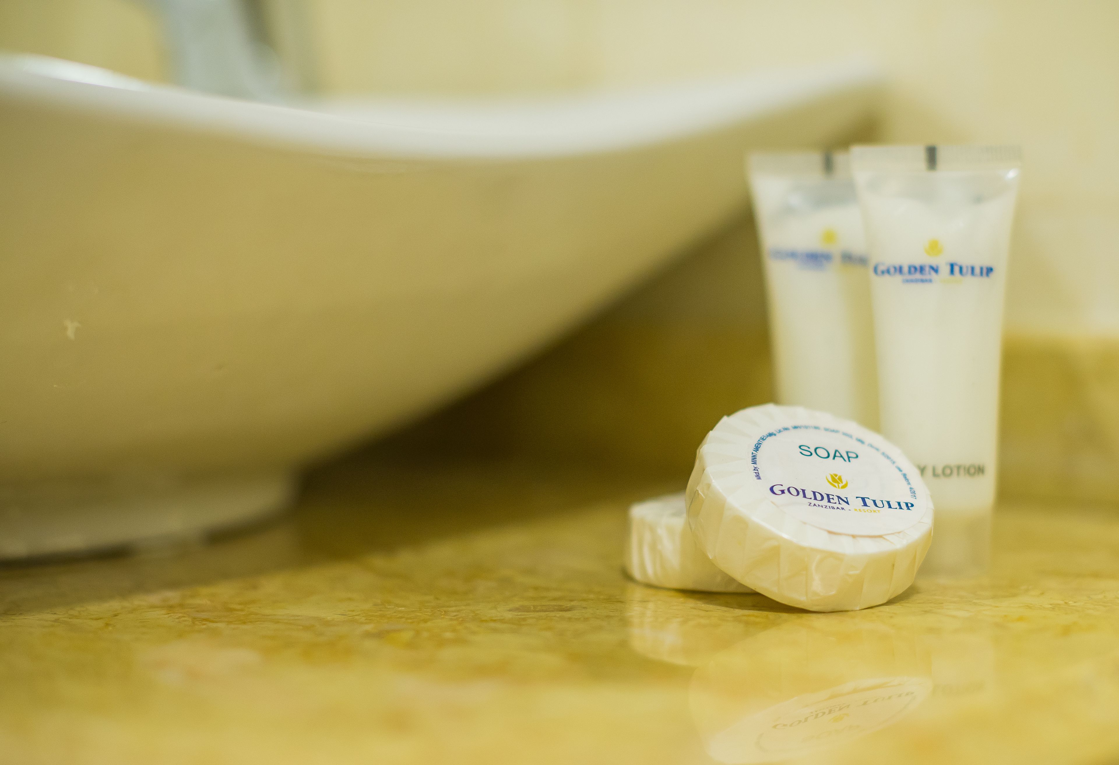 A bathroom sink with a white basin and two tubes of Golden Tulip soap and lotion.