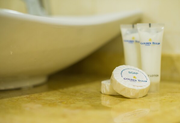 A bathroom sink with a white basin and two tubes of Golden Tulip soap and lotion. - Golden Tulip Zanzibar Resort (Zanzibar Town)