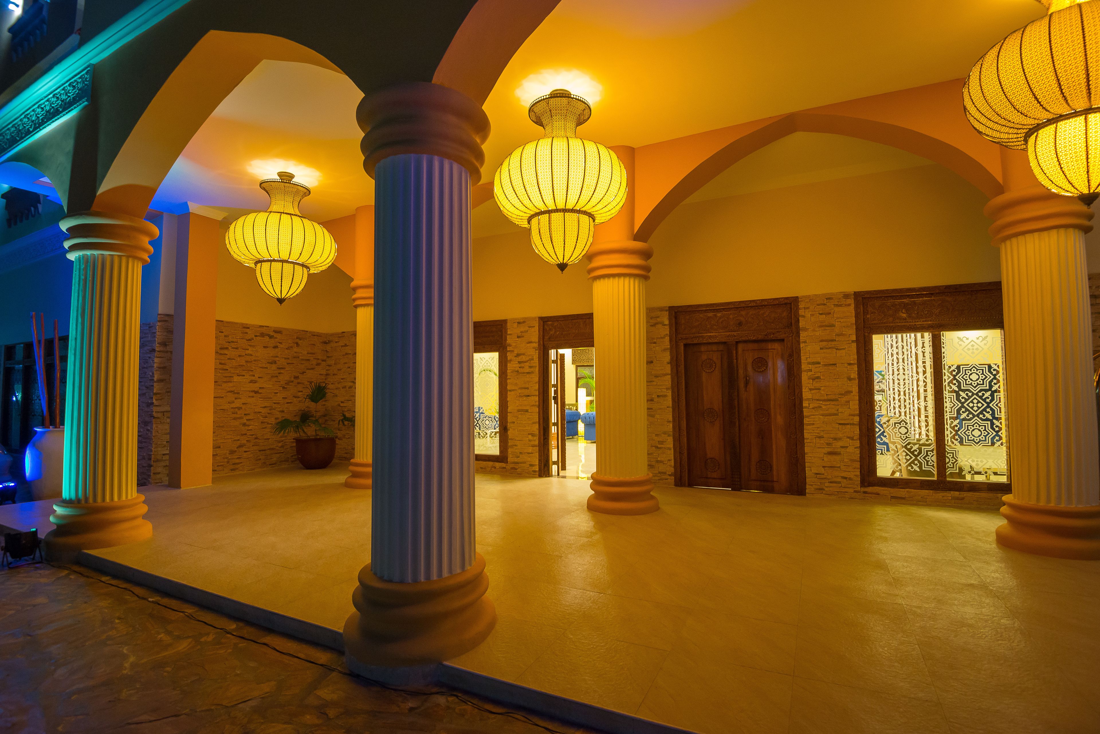 Un vaste hall d’entrée avec de grandes colonnes, des lustres somptueux et un mur en pierre.