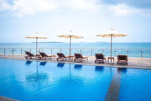 Une piscine dotée de chaises longues et de parasols, avec vue sur la mer.