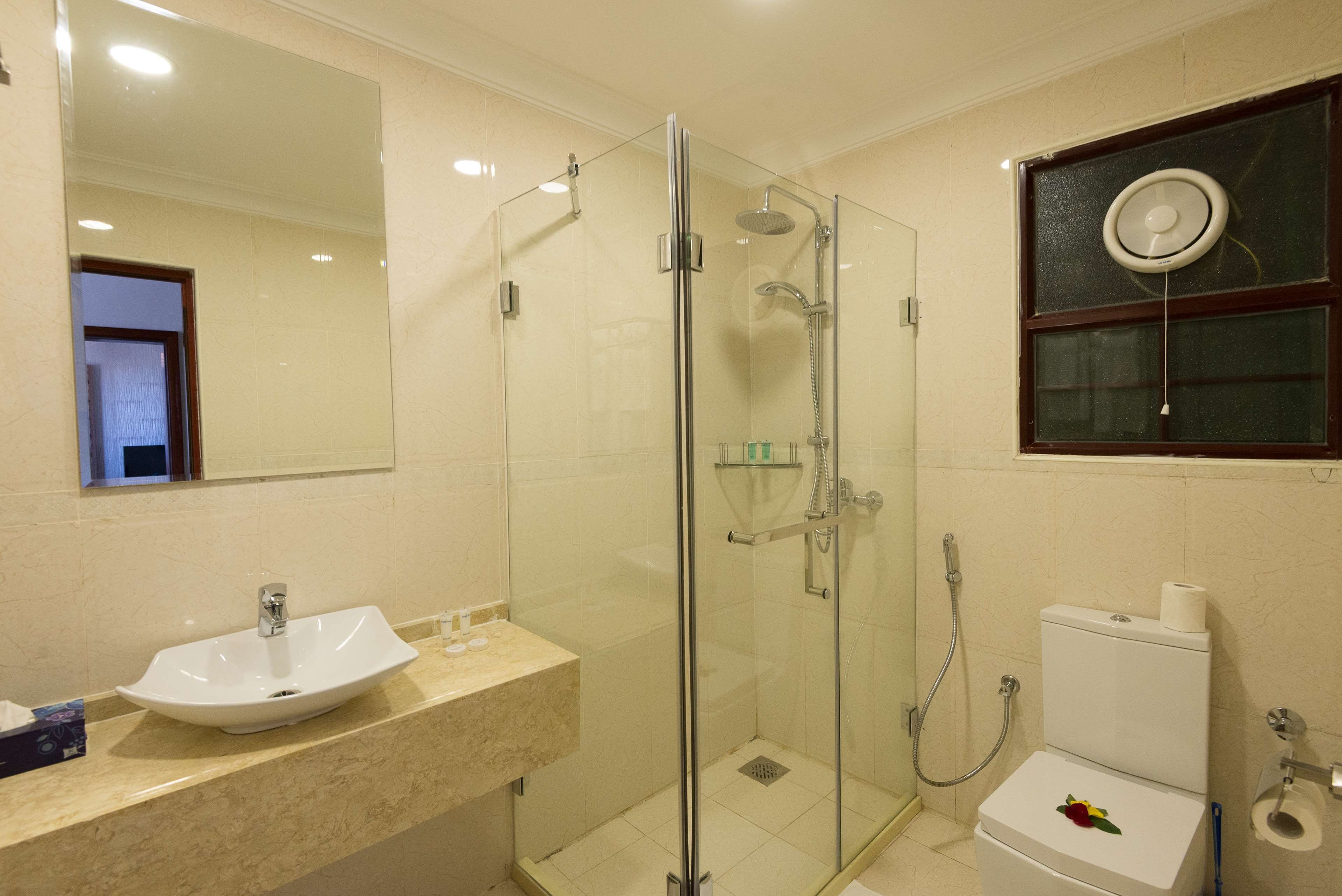 A bathroom with a glass-enclosed shower, a white sink, and a toilet.