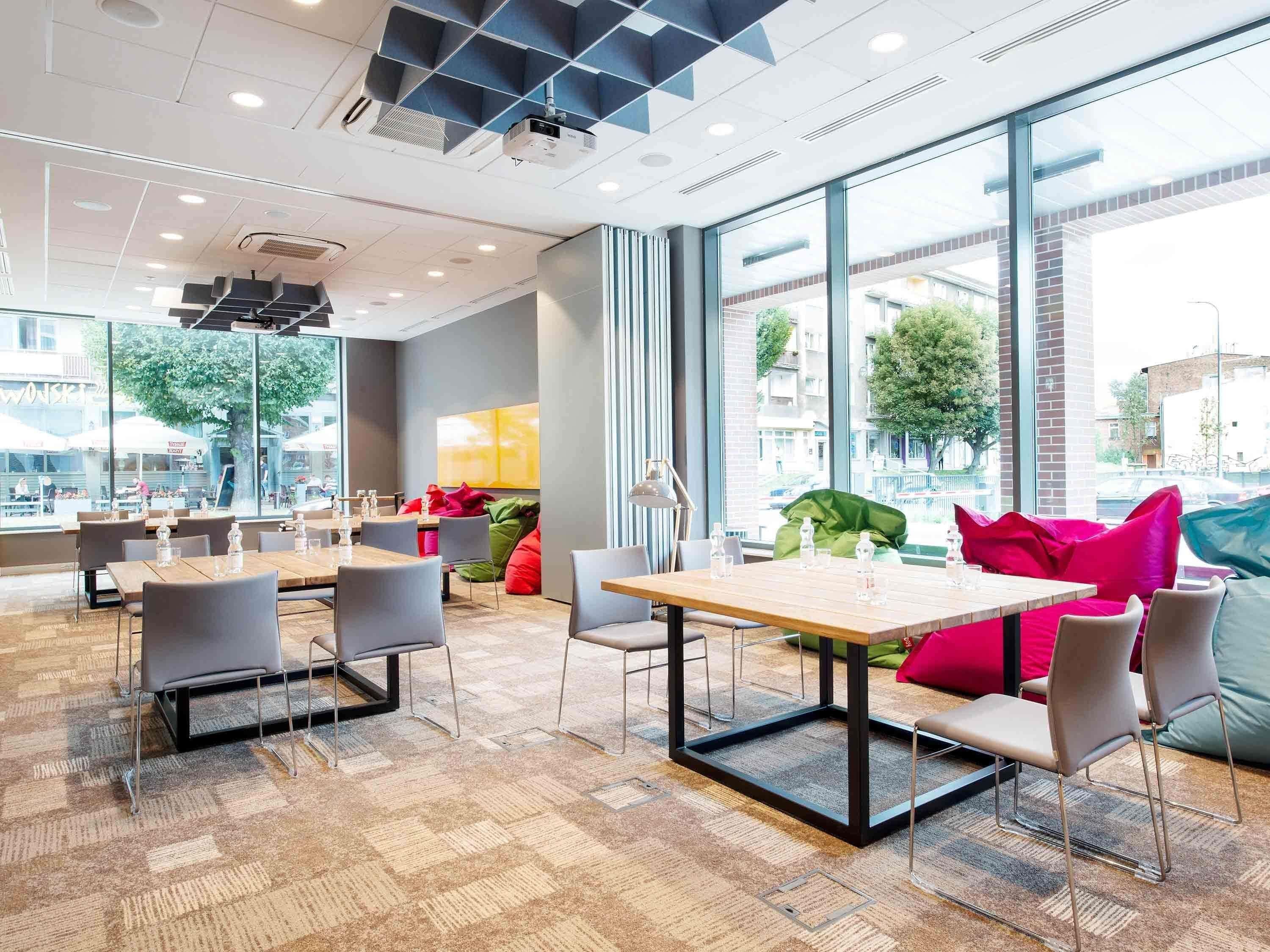 A modern interior with tables and chairs, large windows, and a view of the street.