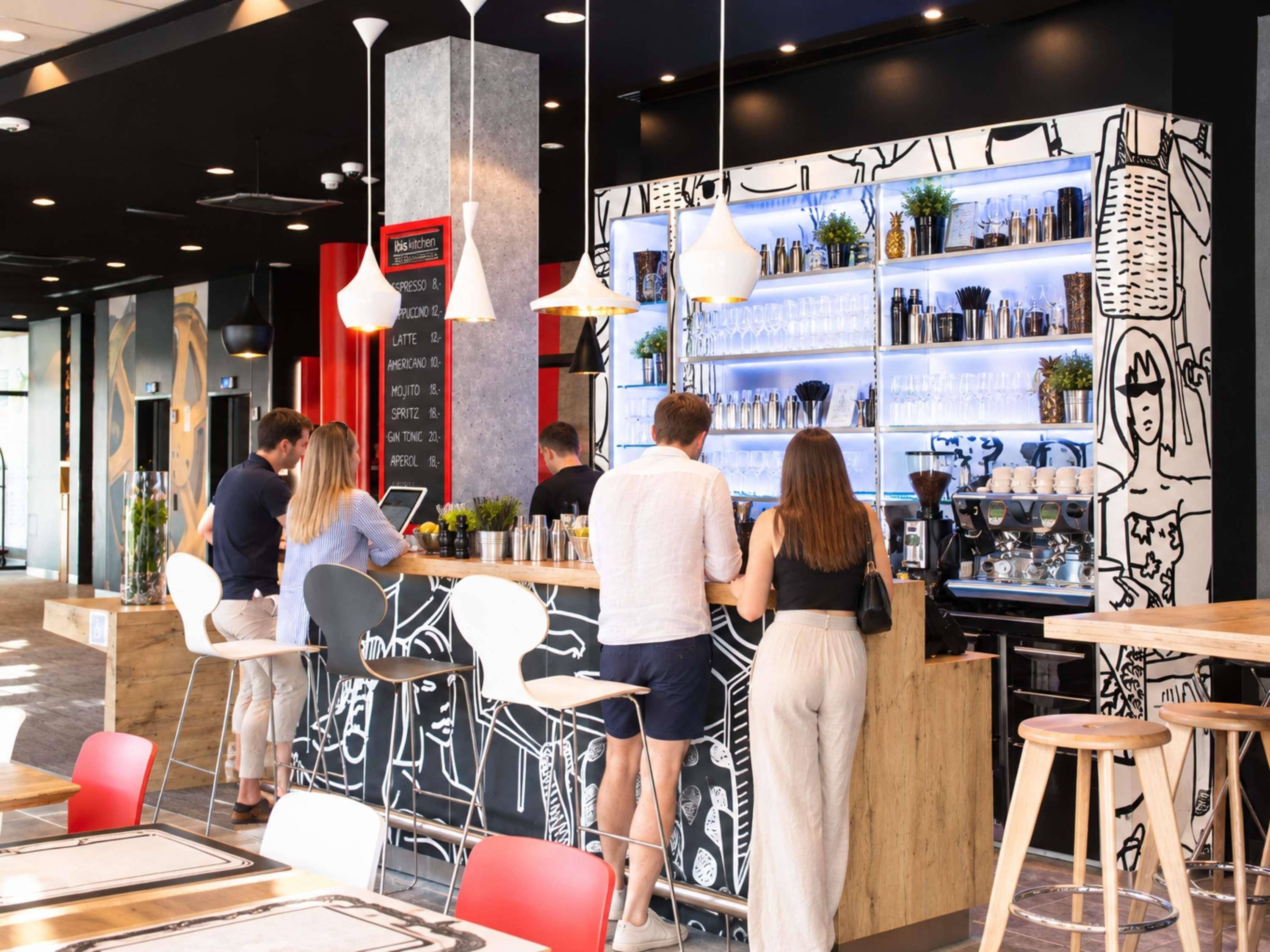 A modern bar area with a menu board, seating, and a barista preparing drinks.