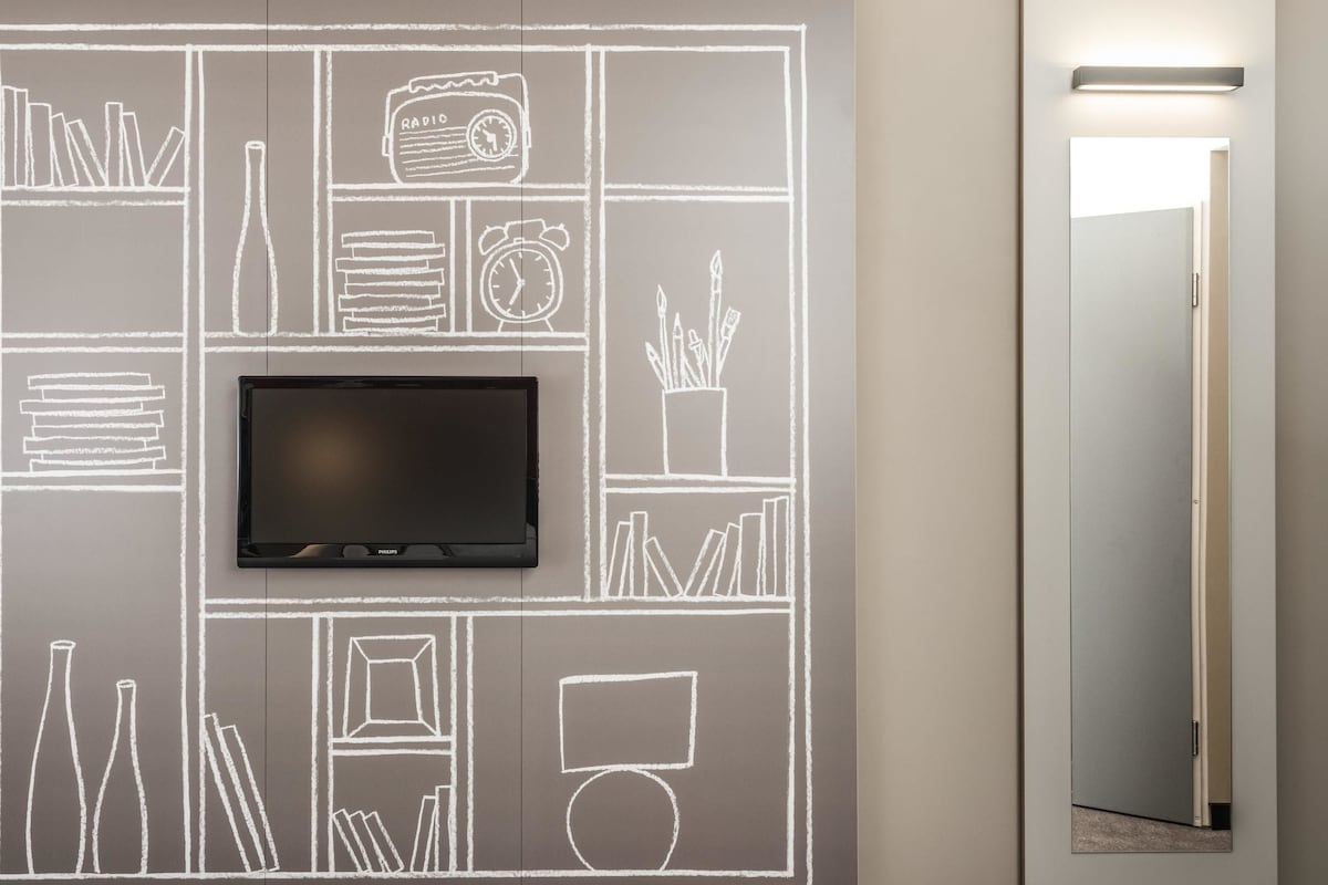 Una habitación moderna con una televisión de pantalla plana montada en una pared de pizarra, un espejo y una puerta.