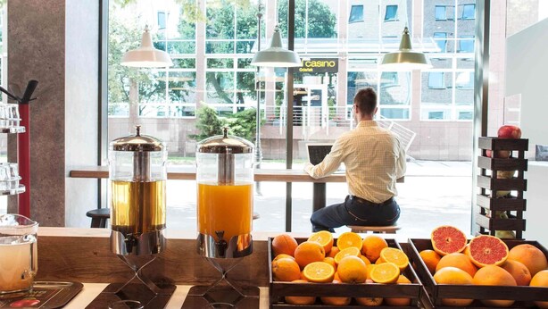 Un área de bar con una persona sentada en una mesa, una exhibición de frutas y una vista de un casino al fondo.