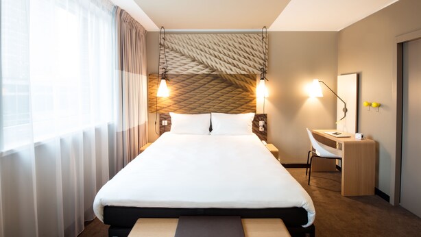 Una habitación de hotel moderna con una cama grande, un escritorio y una silla.