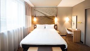 Una habitación de hotel moderna con una cama grande, un escritorio y una silla.