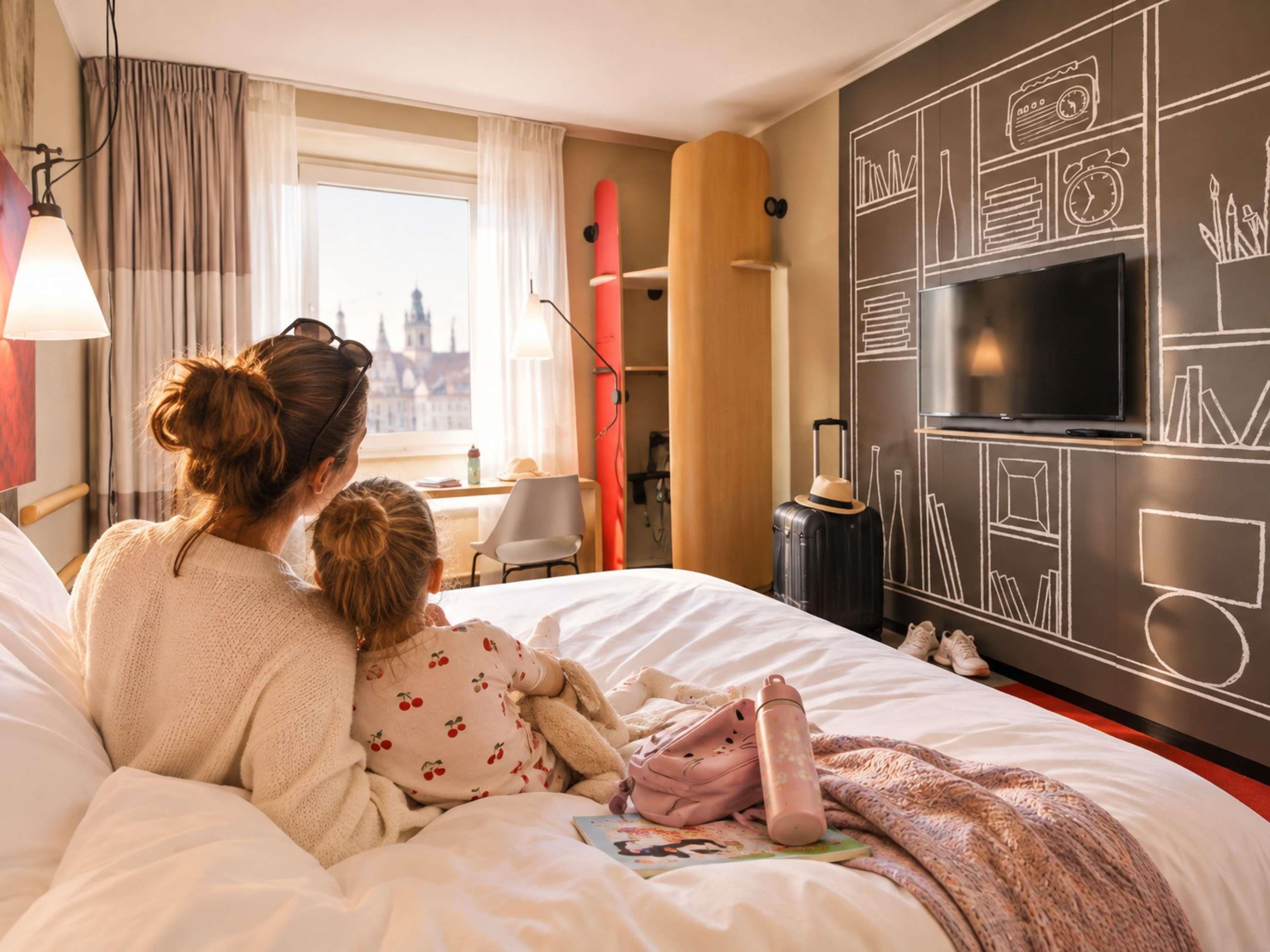 Una habitación de hotel con una cama, una ventana con cortinas, un televisor y una pared con un dise ño de pizarra.