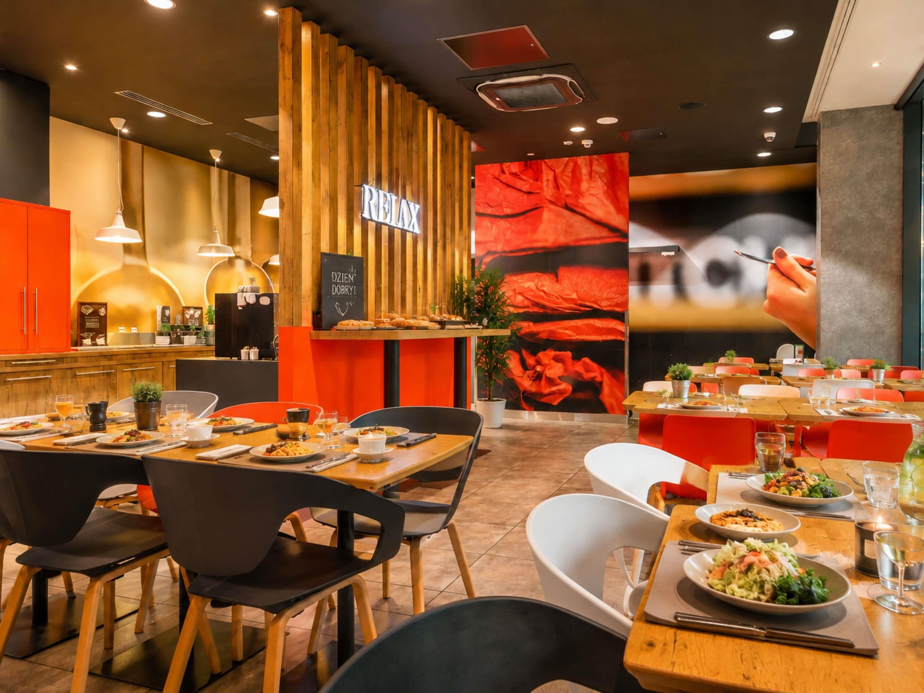 Interior de restaurante con detalles de madera, un cartel con la palabra 'RELAX' y una pared con una imagen floral roja.