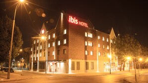 Un hotel con un letrero llamativo que dice "ibis HOTEL" y varias ventanas.