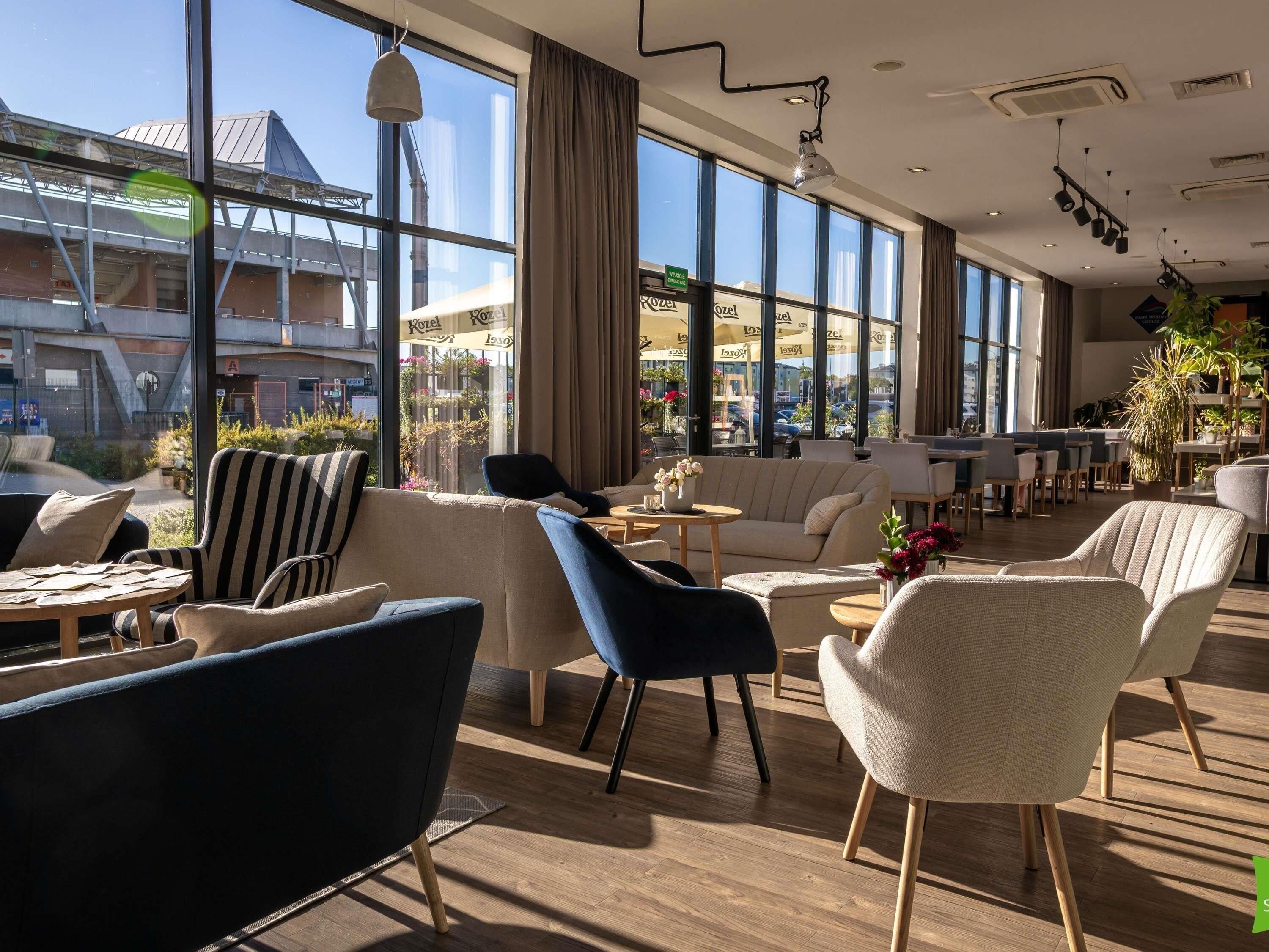 A modern hotel lobby with large windows, comfortable seating, and a view of the cityscape.