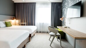 A hotel room with two beds, a desk, a chair, a TV, and a window with curtains. - ibis Styles Siedlce (Siedlce)