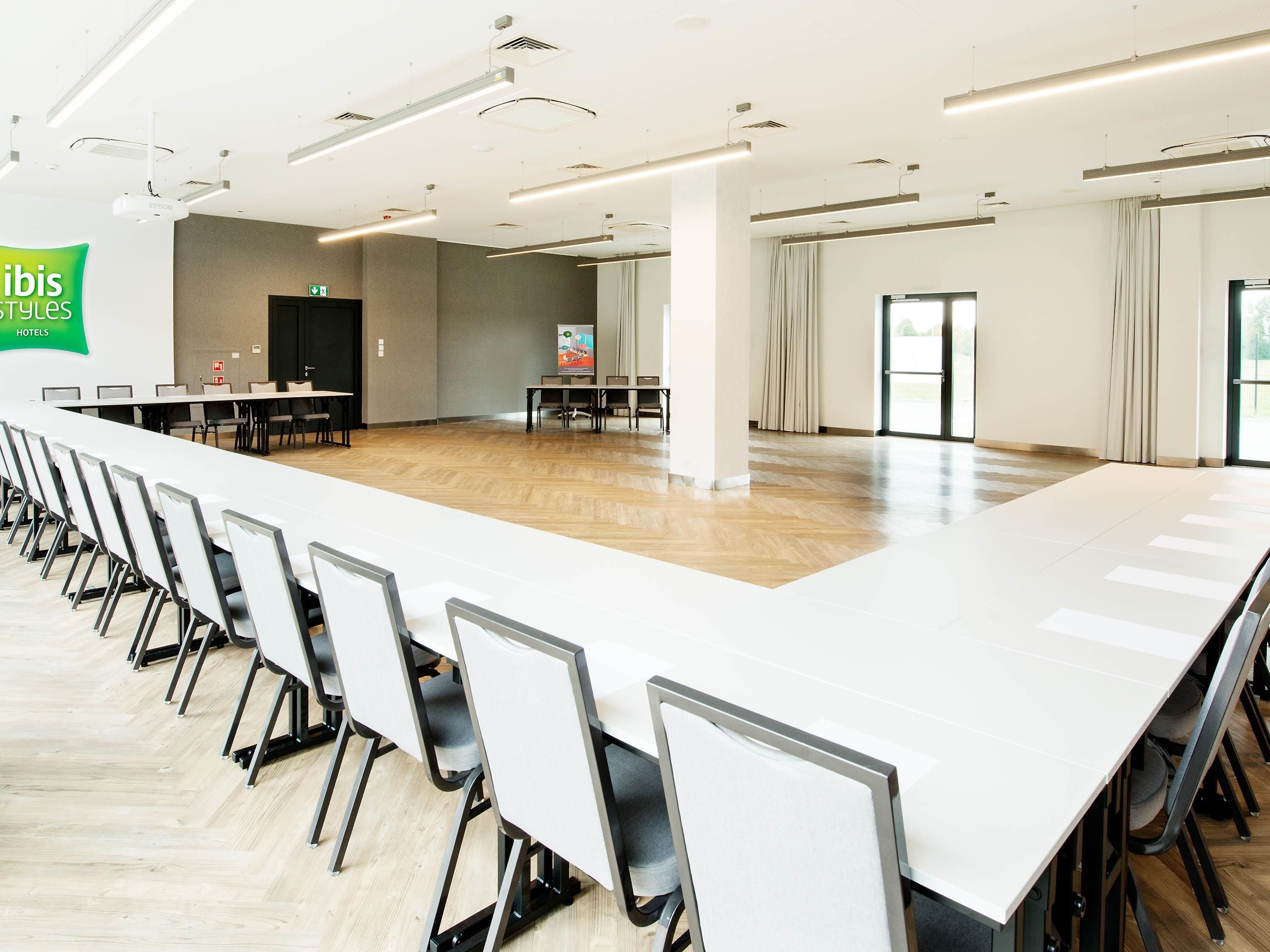 A conference room with a long table and chairs, a projector, and a screen.