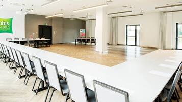 A conference room with a long table and chairs, a projector, and a screen.