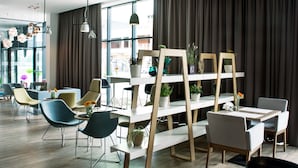 Un interior moderno con una zona de estar, una estantería de madera y vistas a través de grandes ventanales.