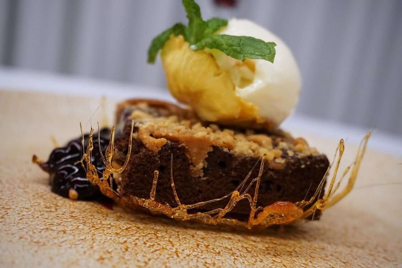 A dessert with a scoop of ice cream and a piece of cake on a textured surface.