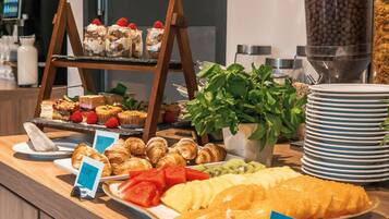 A buffet with various food items including pastries, fruits, and desserts.