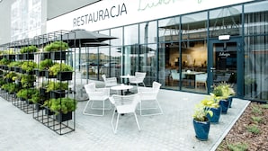 Un restaurante llamado 'RESTAURACJA Lukrecja' con terraza y plantas en macetas.