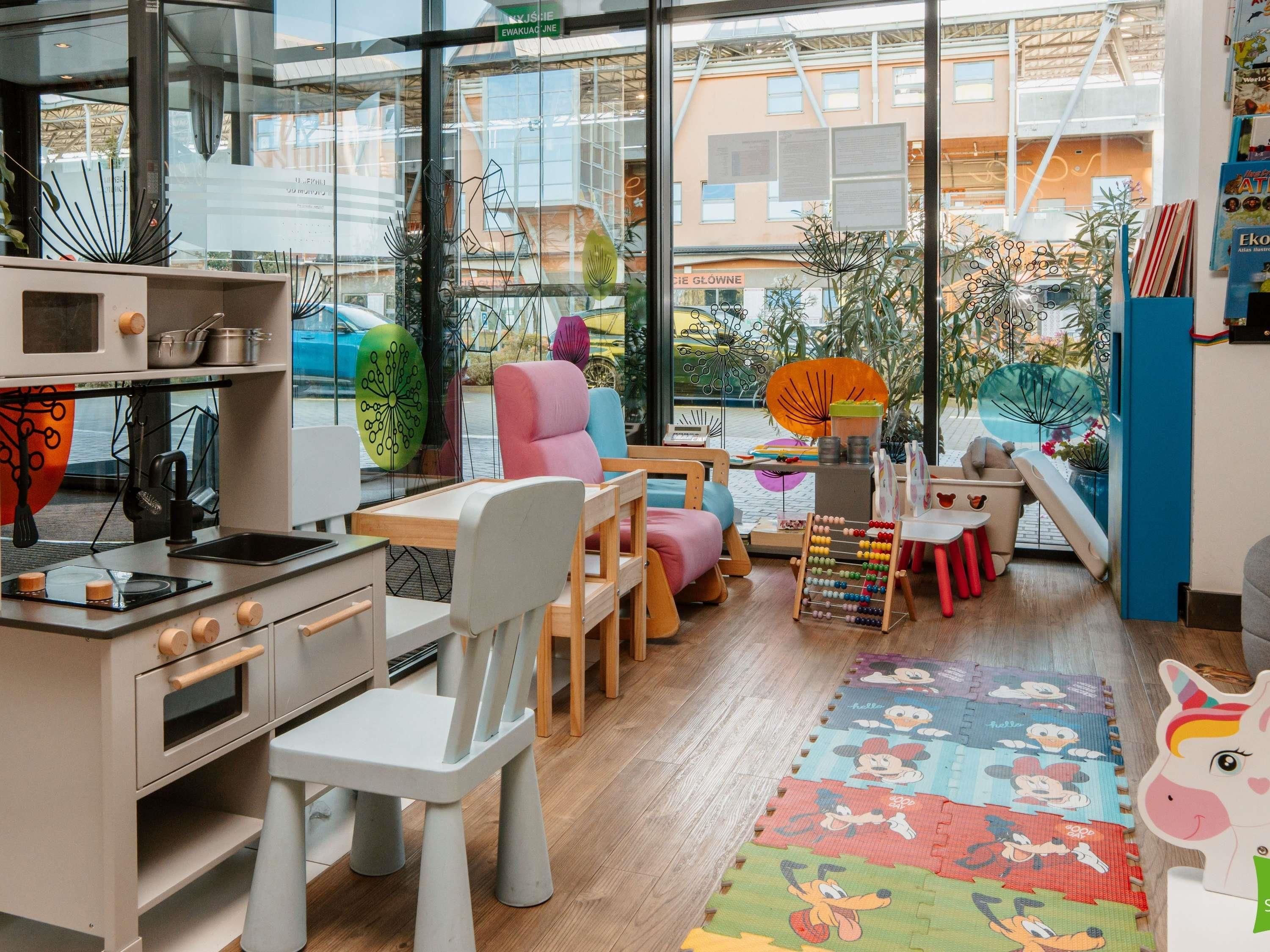 Ein Spielzimmer für Kinder mit Küchenbereich, bunten Möbeln und Blick ins Freie.