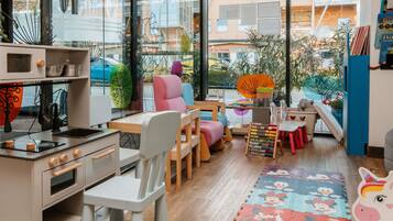 Ein Spielzimmer für Kinder mit Küchenbereich, bunten Möbeln und Blick ins Freie.