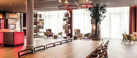 A modern dining area with a long wooden table, multiple chairs, and a unique ceiling light fixture.