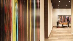 A modern hotel lobby with a large abstract painting on the wall, a wooden floor, and a table with two people playing foosball. - IntercityHotel Braunschweig (Braunschweig)