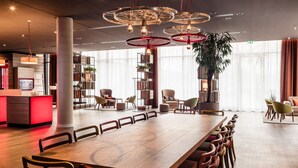 A spacious dining area with a long wooden table, multiple chairs, and a modern chandelier. - IntercityHotel Braunschweig (Braunschweig)