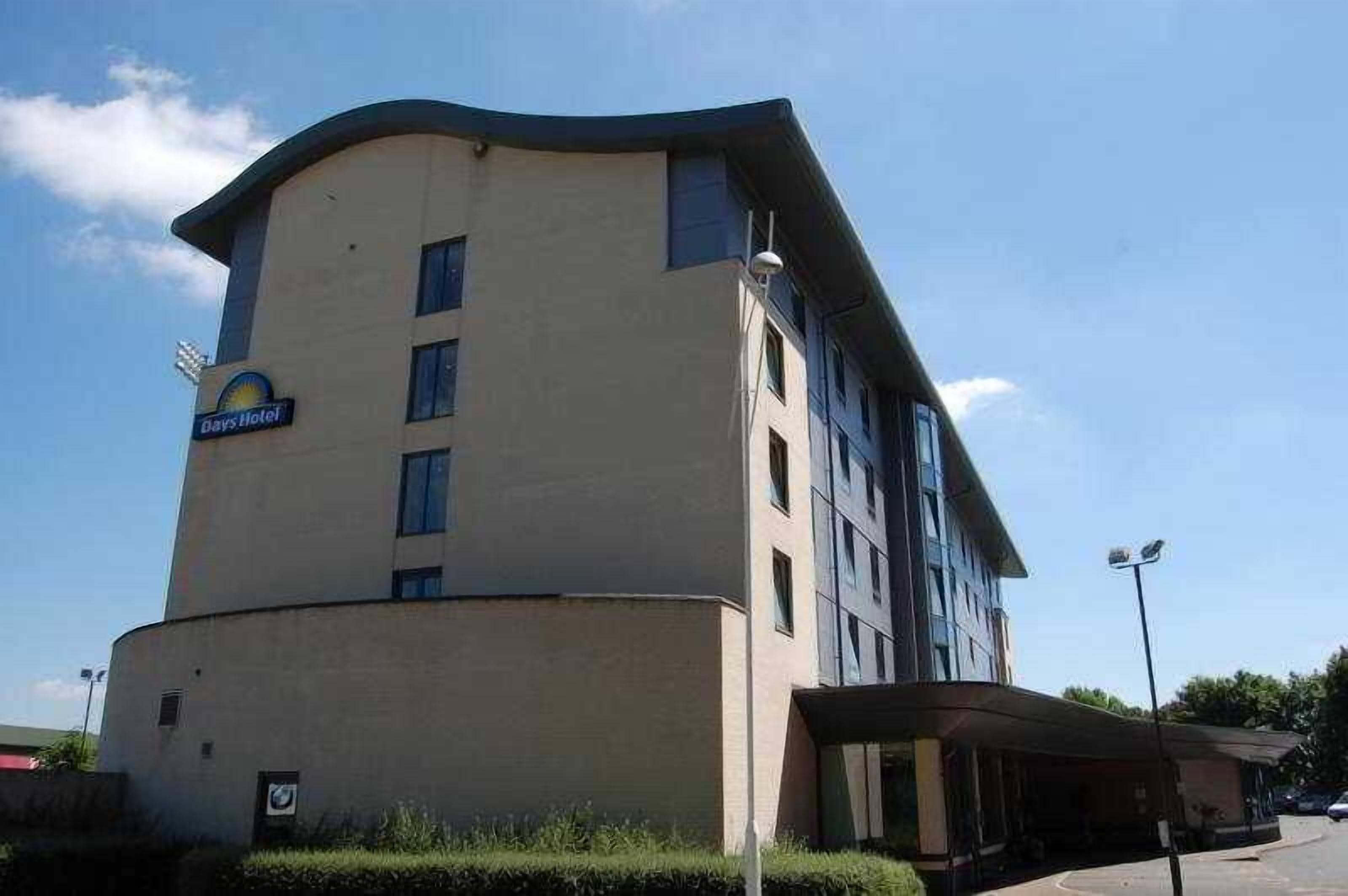 A Days Hotel building with a curved facade, multiple windows, and a covered entrance area.